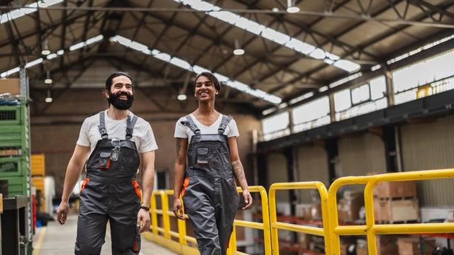 Happy workers walking through warehouse while smiling at each other 